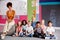 Portrait Of Elementary School Pupils Sitting On Floor In Classroom With Female Teacher