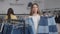 Portrait of embarrassed confused female shopper choosing denim skirt in shop looking at camera smiling. Unsure young