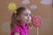 Portrait of emotional girl with big sugar lollipop, kid eat sweets. background of painted sun and white clouds, studio.