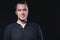 Portrait of an emotional handsome young man, on a black background in the studio, who stands in a brooding pose