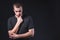 Portrait of an emotional handsome young man, on a black background in the studio, who stands in a brooding pose