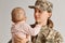 Portrait of emotional military mother, dressed in camouflage, holding her young daughter in arms, greeting after returning home