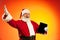 Portrait of emotional Santa Claus with digital tablet, gadget isolated on red yellow background in neon. Merry Christmas