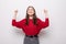 Portrait of energetic woman clenches fists with happiness, has toothy smile, dressed casual red sweater, girl win lottery,