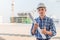 Portrait of engineer wear blue safety helmet and hold the blueprint with commitment on construction site with crane background