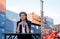 Portrait of engineer worker of factory technician with Chinese woman style sit in front of cargo container crane in workplace area