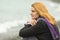 Portrait of enigmatic smiling girl on background of the surf on a cloudy cold day