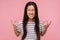 Portrait of enraged furious girl with long hair in striped t-shirt standing with clenched teeth and raised hands