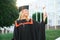 Portrait enthusiastic female college student graduate in cap and gown celebrating, holding diploma.