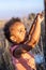 A portrait of an ethiopian mixed etnicity interracial child toddler holding a barbed wire fence looking worried and sorrowful.