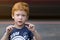 Portrait European boy with green eyes. Child with curly ginger hair. Talking with sign language. Boy talking nonverbal