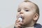 Portrait european caucasian baby toddler funny thrusts a pacifier into his mouth and looks at the camera, holds on to