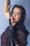 Portrait of a European woman with a sword in her hands. Shooting in the studio. Close-up, red lipstick, model in a black cape