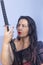 Portrait of a European woman with a sword in her hands. Shooting in the studio. Close-up, red lipstick, model in a black cape