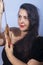 Portrait of a European woman with a sword in her hands. Shooting in the studio. Close-up, red lipstick, model in a black cape