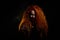 Portrait of an evil red-haired witch conjures in the dark.