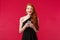 Portrait of excited and amused, redhead woman wearing black dress on her date or prom night, holding mobile phone