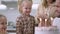 Portrait of excited baby girl clapping and laughing blowing candles on birthday cake. Happy Caucasian little daughter