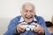 Portrait of excited elderly man playing video game at home