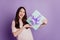 Portrait of excited funny beautiful woman receive box gift on purple wall