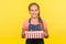 Portrait of excited glad little girl in denim overalls holding gift box and smiling to camera, satisfied with birthday present