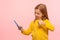 Portrait of excited little girl smiling and gesturing thumb up to mobile phone, showing like, approval sign