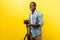 Portrait of excited motivated photographer posing professional digital dslr camera on tripod. studio shot isolated on yellow