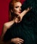 Portrait of excited seductive rich sensual young red-haired woman standing naked covering herself with luxury fur coat