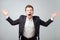 Portrait of excited young male in suit screaming in shock and amazement holding hands up.