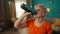 Portrait of an exhausted grayhaired elderly woman after a workout in the living room. Tired elderly woman drinks water