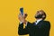 portrait of expressive happy excited bearded man in suit and tie with smartphone video call hand up celebrating yellow