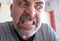 Portrait of an extremely angry middle-aged Caucasian man: bloodshot eyes are staring down at the side. The gritted teeth and the