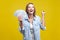 Portrait of extremely happy woman holding fan of dollars showing yes i did it gesture.  on yellow background