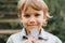 Portrait of the face of a cute happy smiling little five year old dishevelled long blond dark eyed caucasian preschool kid boy hol