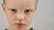 Portrait of fair-haired displeased child, an angry boy with an angry expression on his face looks at camera. Portrait