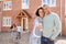 Portrait Of Family Holding Keys Standing Outside New Home On Moving Day