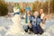 Portrait of a family with snowman. happy children and parents in the winter outdoors