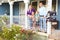 Portrait Of Family Standing On Porch Of Suburban Home