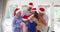 Portrait of family wearing santa hats smiling and standing together in the living room at home