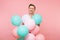 Portrait of fascinating young happy man wearing striped t-shirt holding colorful air balloons isolated on bright