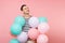 Portrait of fascinating young happy man wearing striped t-shirt holding colorful air balloons isolated on bright