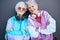 Portrait, fashion and friends with a senior woman pair standing arms crossed outdoor on a gray wall background