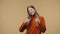 Portrait of fashion model showing thumbs up, gesture like. Young stylish girl with long hair in orange sweater posing on