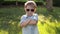 Portrait of a fashionable little boy in sunglasses in a park on green grass.