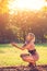 Portrait of fashionable young sensual blonde woman in garden enyoing on the grass field at sunset