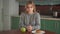 Portrait of a fat girl making a choice between healthy and unhealthy food sitting at the table in the kitchen. The fat