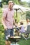 Portrait Of Father Cooking Barbeque For Family In Garden At Home