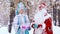 Portrait of Father Frost and smiling Snow Maiden showing gifts to the camera