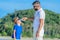 Portrait of father giving water to his thirsty handsome boy on the desert tropical beach.