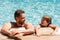 Portrait of father and son relax in swimming pool. Pool resort. Happy family face. Copy space.